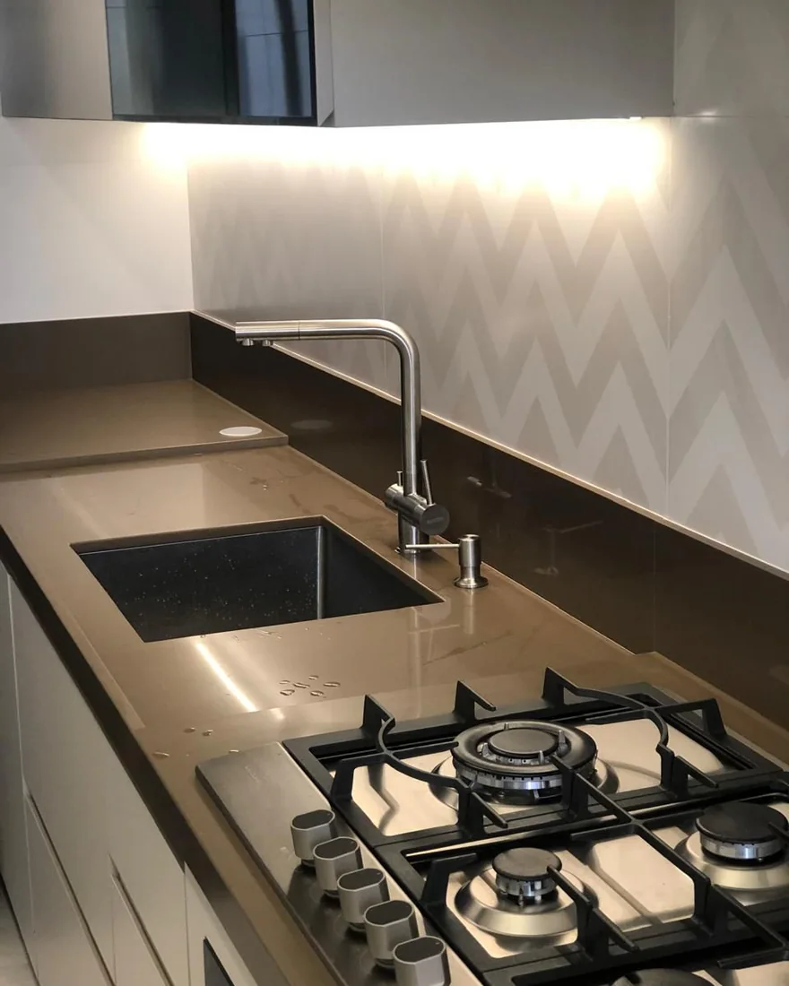 Cozinha com revestimento em zigue-zague, cuba preta e iluminação sob o armário