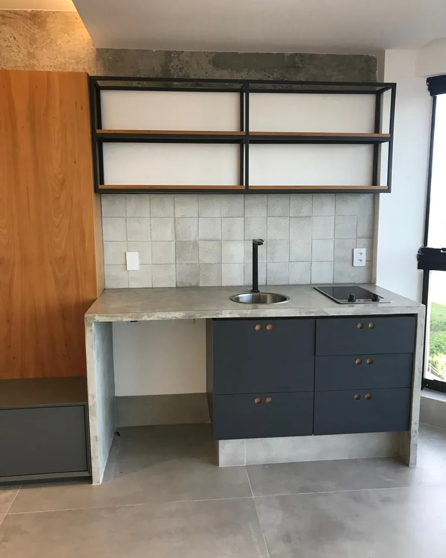 Cozinha com estrutura metálica, marcenaria azul e bancada em pedra
