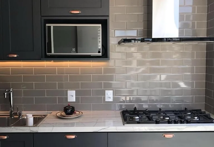 Cozinha reformada com marcenaria grafite, revestimento metrô e bancada em pedra